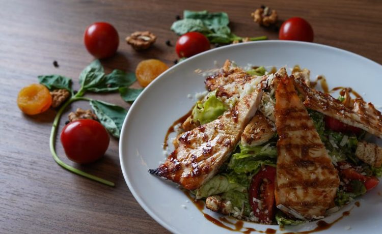 Delicious grilled chicken salad served with fresh tomatoes and walnuts on the side.