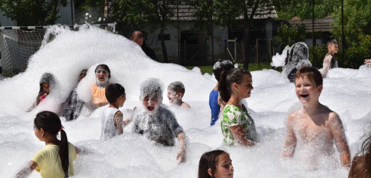 Children having fun in a foam party outdoors during summer.